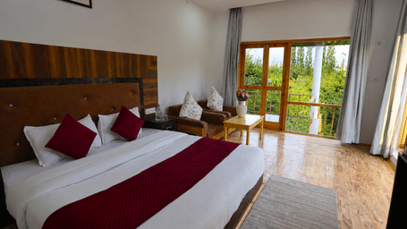 A room with a large bed, pillows, spreads, and windows leading to the nature | Indus Serinity, Leh Ladakh