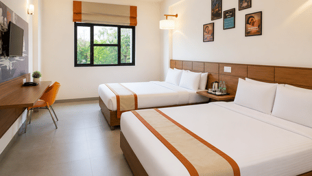 Spacious Max Family Room at Max Hotel Jabalpur featuring twin beds, a seating area, work desk and ample natural light.