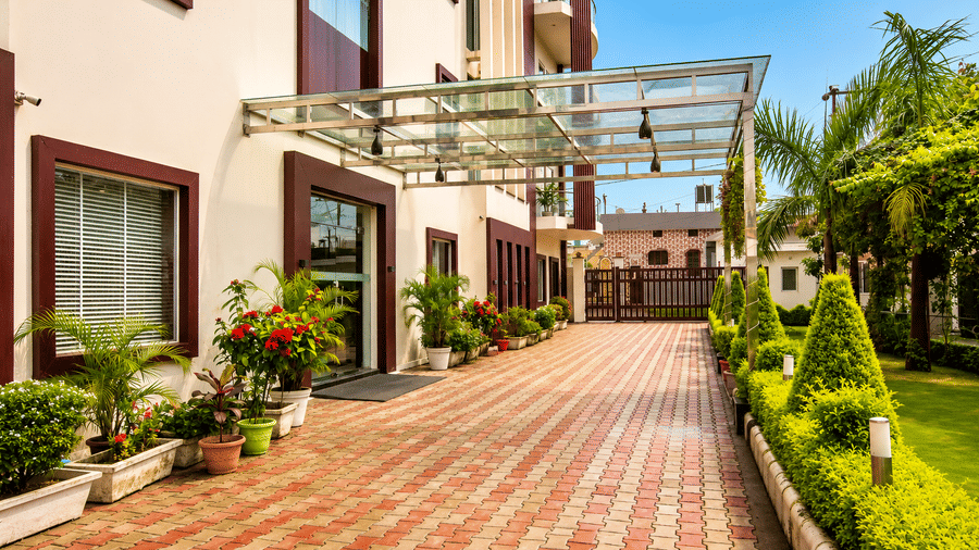 Covered entrance driveway with a brick pathway and landscaped garden at Eastlynn Resort, Rishikesh.