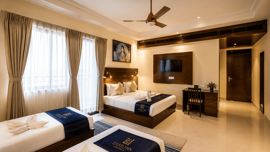 Family Room with Balcony featuring twin beds, a ceiling fan and wall art at Eastlynn Resort, Rishikesh.
