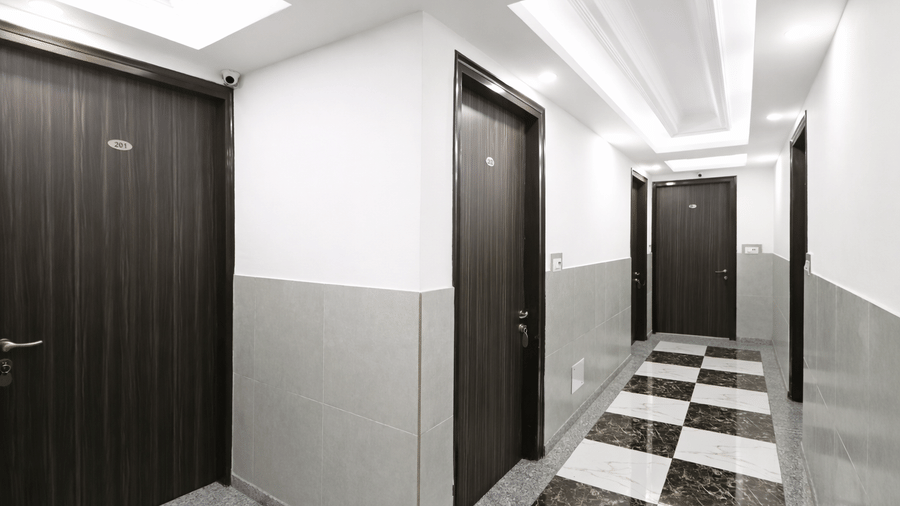 Long hallway view showing a series of guest room doors and recessed ceiling lighting.