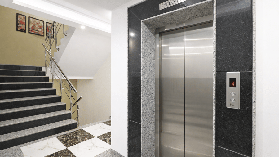 Clean and minimalist elevator lobby with a stainless steel elevator door and marble flooring.