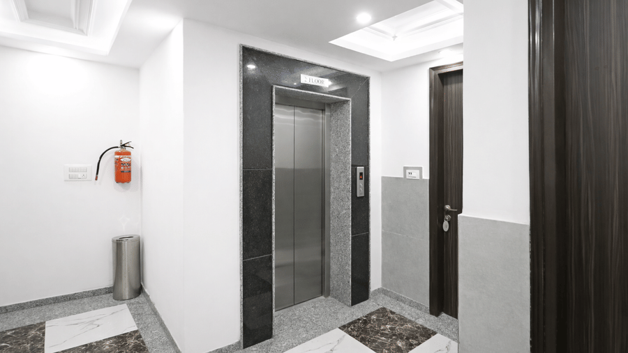 A clean, modern hotel hallway with white walls, dark door frames, and polished marble flooring.