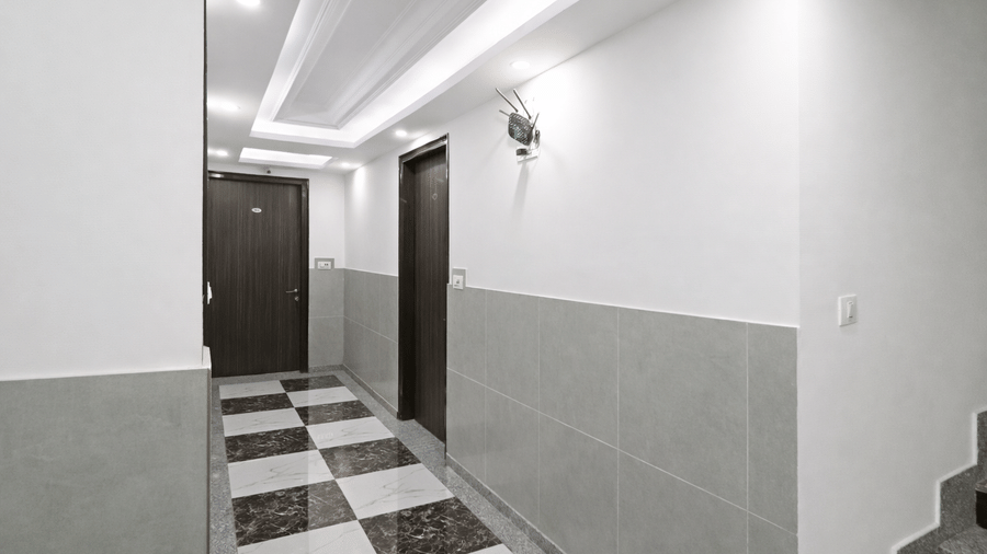 The lift landing at Hotel Apple Park Delhi, showing a stainless steel lift with a black marble surround and a stone staircase to the left.