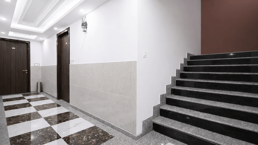 A wide marble staircase with dark railings leading up to the next floor in a brightly lit hotel interior.