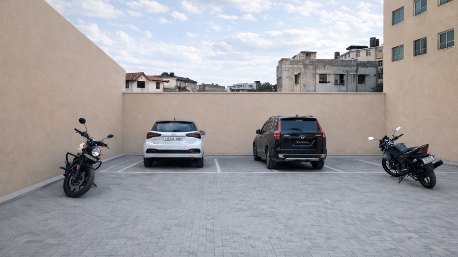 Rows of cars and motorcycles parked in front of multi-storey building.