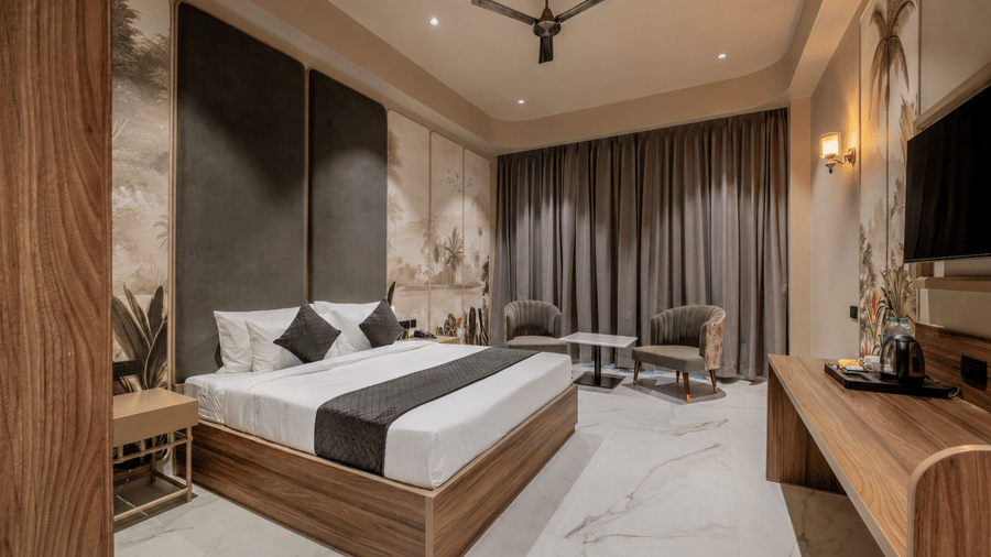 Bedroom with a double bed, wooden wardrobe, television, and upholstered seating.