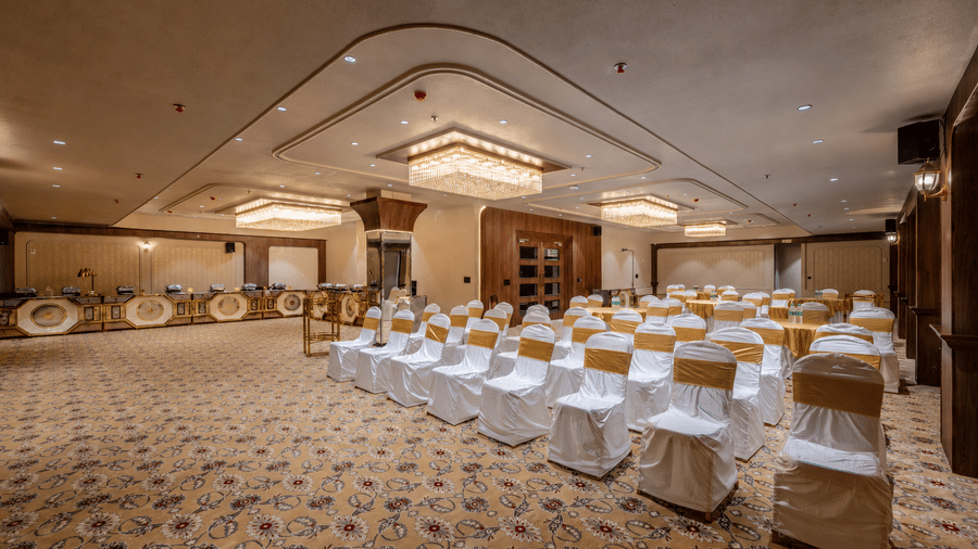 Banquet hall arranged with round tables and covered chairs for an event.
