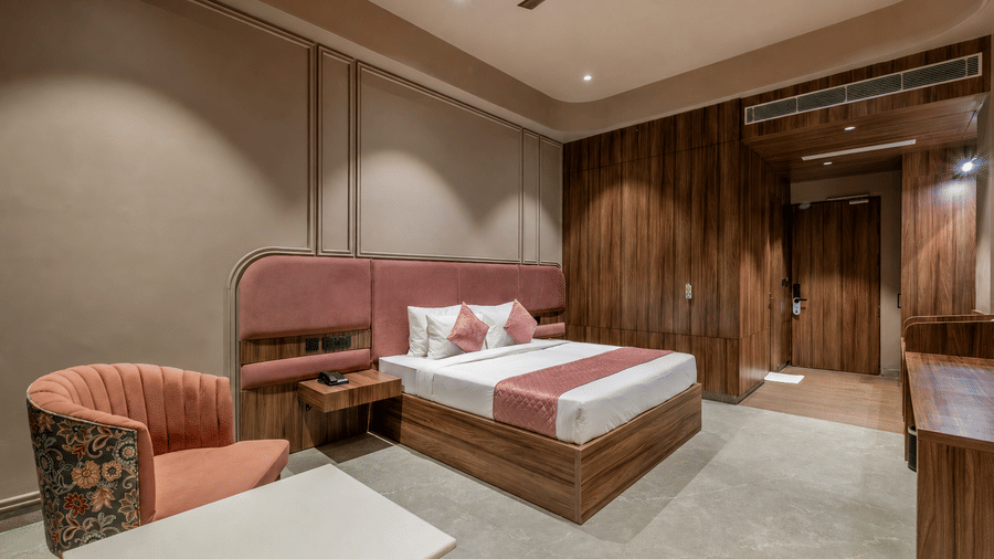 Bedroom with a double bed, wooden wardrobe, sofa seating, and bedside tables.