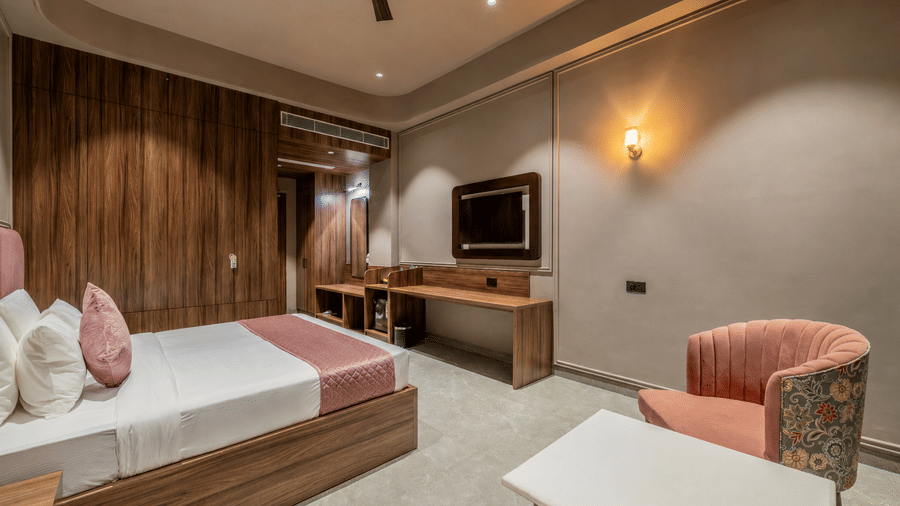 Bedroom with a double bed, television, sofa seating, and wooden wall panels.