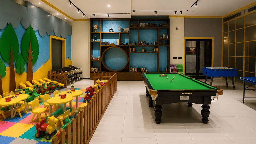 A recreational room at Hotel Sonar Bangla, Mayapur, featuring a snooker table, small tables, and wall shelving units.