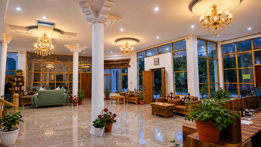 A lobby with pillars, chandeliers, plants, sofas and chairs. | Indus Serinity, Leh Ladakh