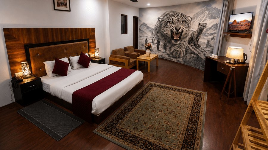 A room with a large bed, pillows, spreads, wall mounted art works, carpets, lamps, and a tiger wallpaper. | Indus Serinity, Leh Ladakh