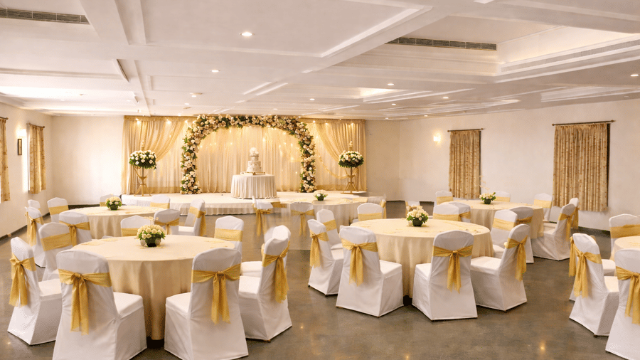 A beautifully decorated banquet hall for a wedding reception with round tables and gold accents - Jenneys Residency, Coimbatore.