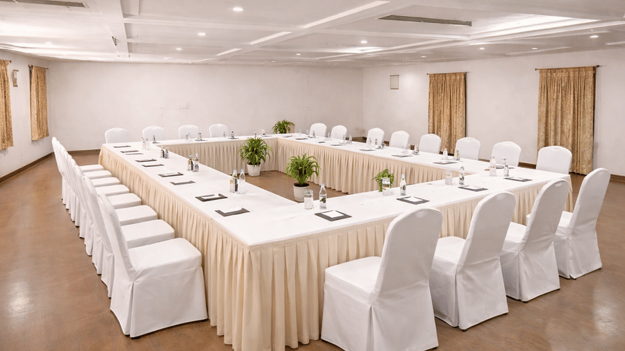 A bright meeting room configured in a U-shape with white linens for a corporate presentation - Jenneys Residency, Coimbatore