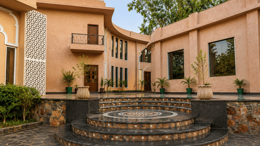 Heritage property building with a stone fountain in the foreground and lush greenery at Kadamb Kuteer, Vrindavan.