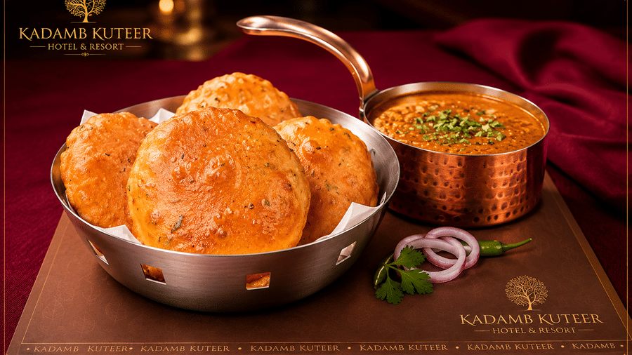 Puri served with chole and dal in brass bowls on a branded placemat at Kadamb Kuteer, Vrindavan.