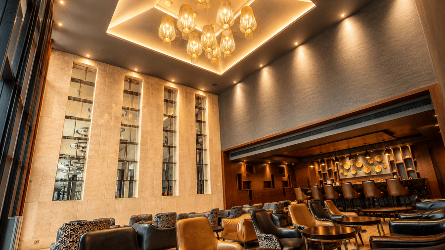 Modern bar lounge featuring high ceilings, warm lighting, and seating at Kiranshree Grand Hotel.