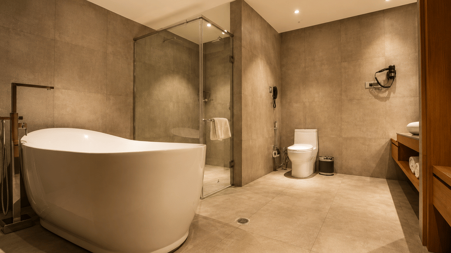 Modern bathroom with a freestanding bathtub and glass shower in the Suite at Kiranshree Grand Hotel.