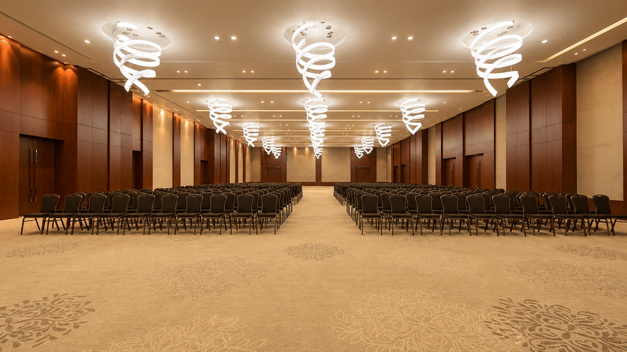 Grand banquet hall set up with theatre seating and spiral chandeliers at Kiranshree Grand Hotel.