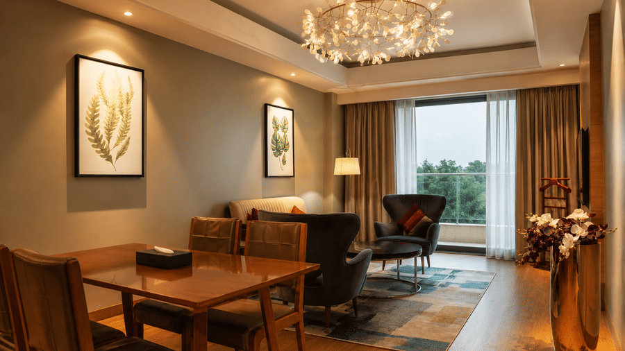 Spacious living and dining area with modern chandelier in the Grand Suite at Kiranshree Grand Hotel.