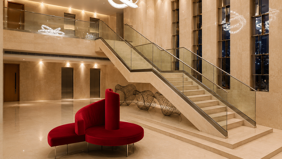 Modern hotel lobby featuring a grand staircase and striking red seating at Kiranshree Grand Hotel.
