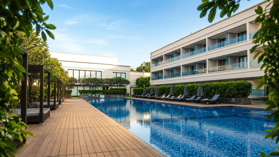 Outdoor swimming pool with poolside loungers and hotel building view at Kiranshree Grand Hotel.