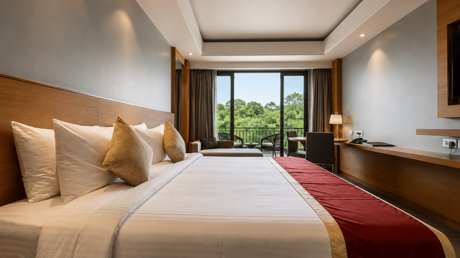 King bed arrangement with large window views in the Presidential Suite at Kiranshree Grand Hotel.