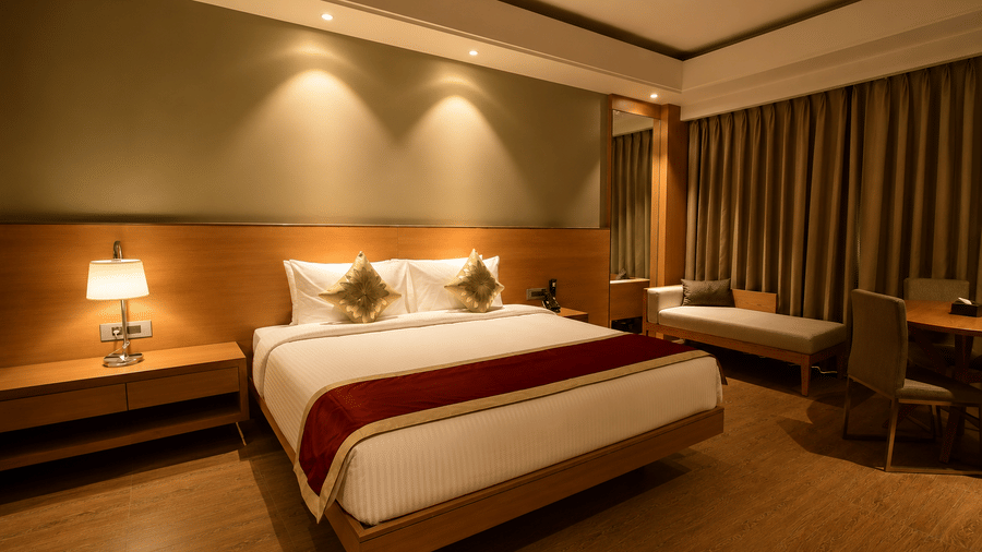 Bedroom with king bed, red runner, and warm ambient lighting in the Presidential Suite at Kiranshree Grand Hotel.