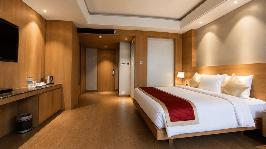 King size bed with warm wooden panelling in the Royal Club Room at Kiranshree Grand Hotel.