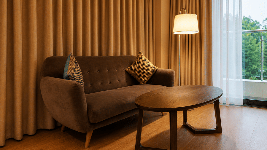 Cosy seating area with a plush sofa and wooden coffee table in the Royal Club Room at Kiranshree Grand Hotel.