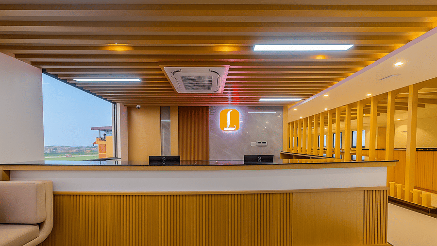 A reception area featuring a white counter, wooden ceiling slats and recessed lighting | Lords CBC Plaza, Chitwan