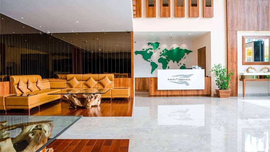 The bright and modern lobby of Mansha Palace features comfortable seating and a reception desk with a world map backdrop.