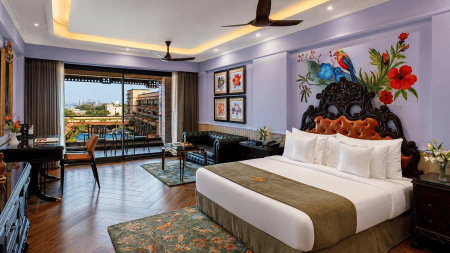 A neatly-made bed and balcony with distant port views in a Premium Port View Room at MAYFAIR Bay Resort, Paradeep.