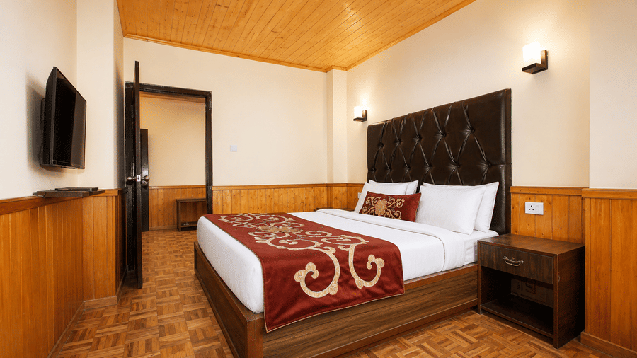 Imperial Suite at Orsino Khangri Karpo Retreat & Spa, Lachung featuring a bed, a bedside table and a flat TV screen mounted on the wall.