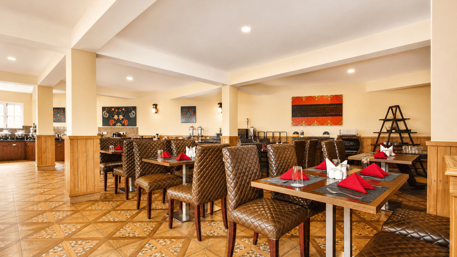 Orion restaurant at Orsino Khangri Karpo Retreat & Spa, Lachung featuring a large indoor space with patterned flooring features several wooden tables and chairs.