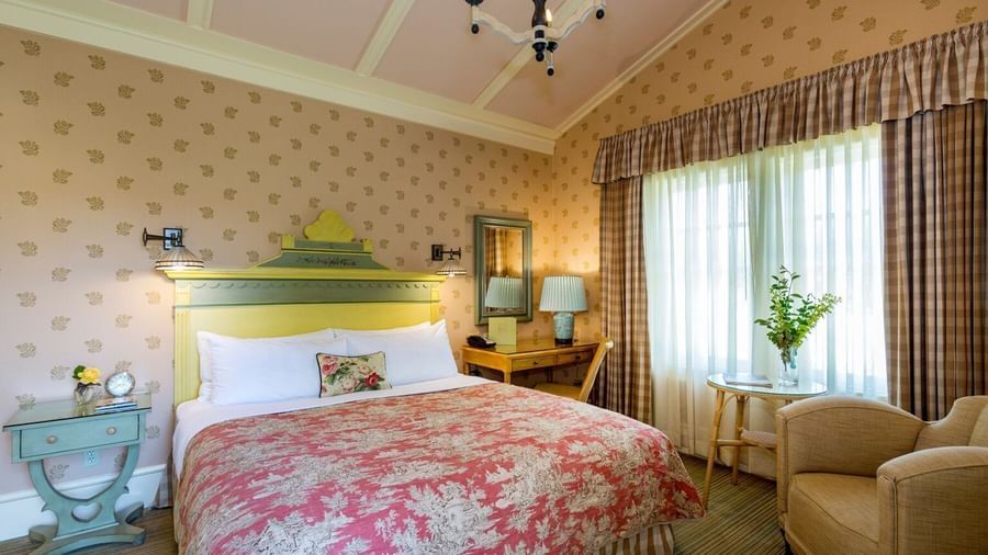 A charming and comfortable guest room at the Tallman Hotel, with a sloped ceiling, a double bed, and elegant decor.