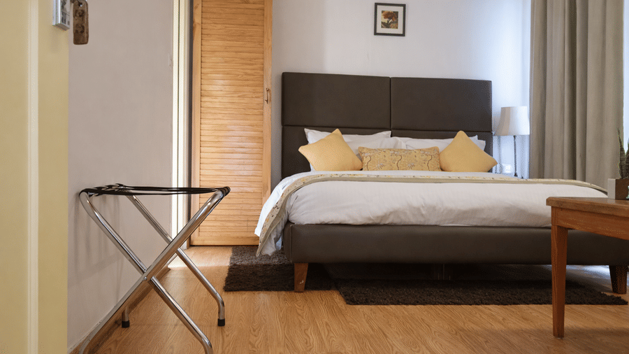 Bedroom with double bed, wooden flooring, bedside lamps and luggage rack at The Pinewood, Nainital.