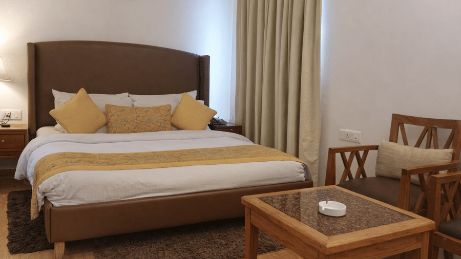 Spacious bedroom with double bed, side tables and seating area at The Pinewood, Nainital.