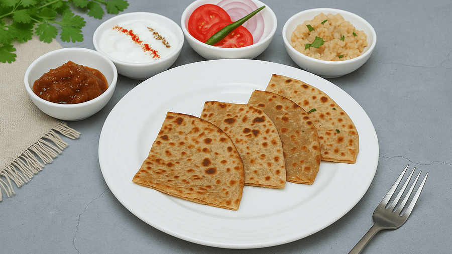 Parathas served with chutney, pickle, and salad on a white plate at Tisya Farms, Gurgaon.
