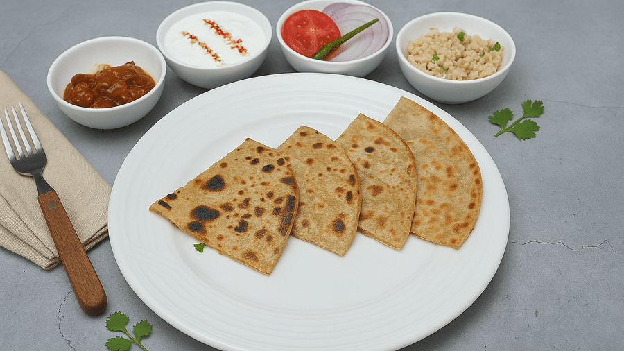 Parathas served with curd, pickle, chutney, and salad on a white plate at Tisya Farms, Gurgaon.