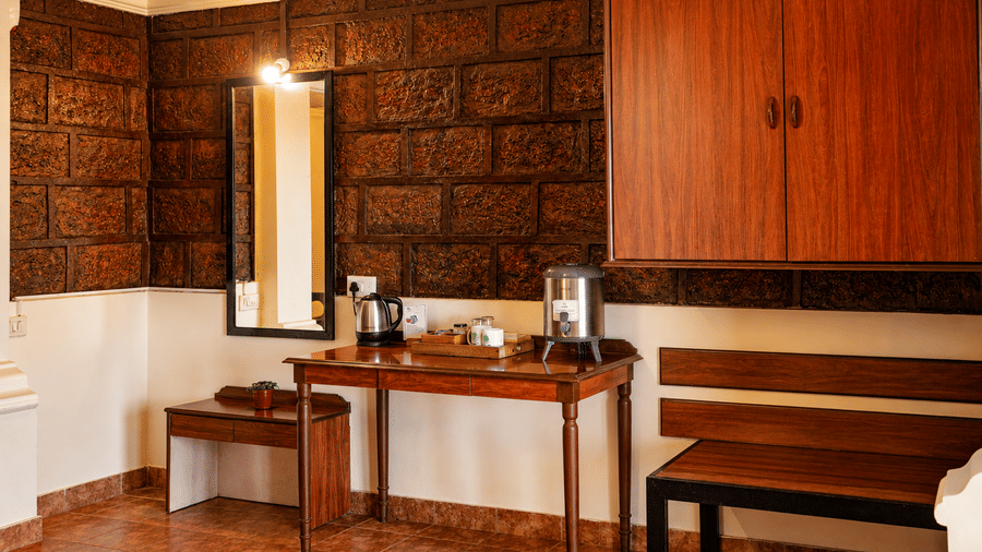 Wooden tea station, mirror, and bench set against exposed brick walling inside a guest room at Wind Chalet property.