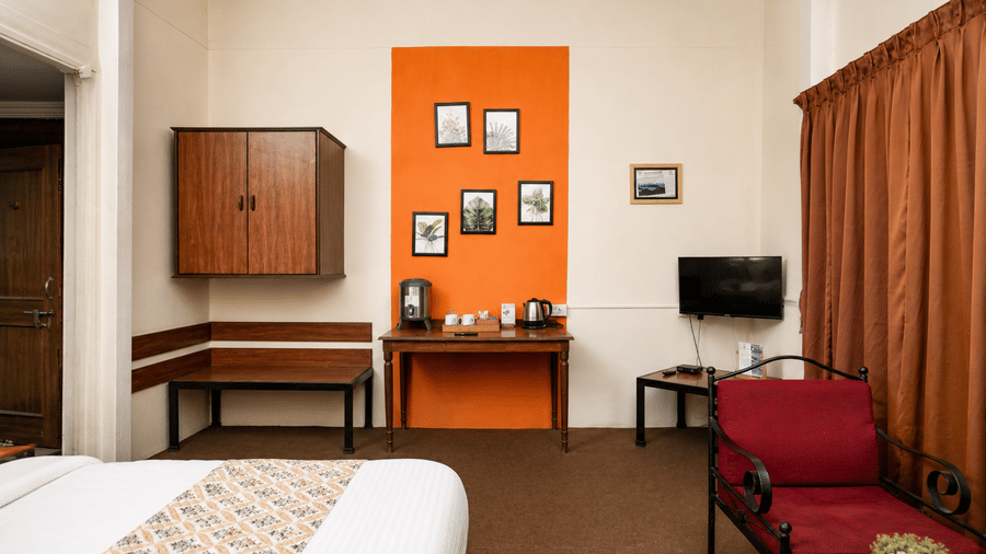 Cosy Wind Chalet bedroom area featuring a red armchair, orange accent wall, mini bar console, and bed runner.
