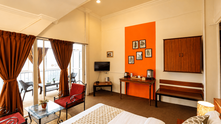 High-angle view of a Wind Chalet bedroom showing double bed, red armchairs, tea desk, and orange feature wall.