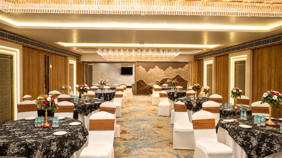 Elegant tables and chairs are carefully arranged inside a brightly lit function room - Lords Inn Sangam, Bhopal