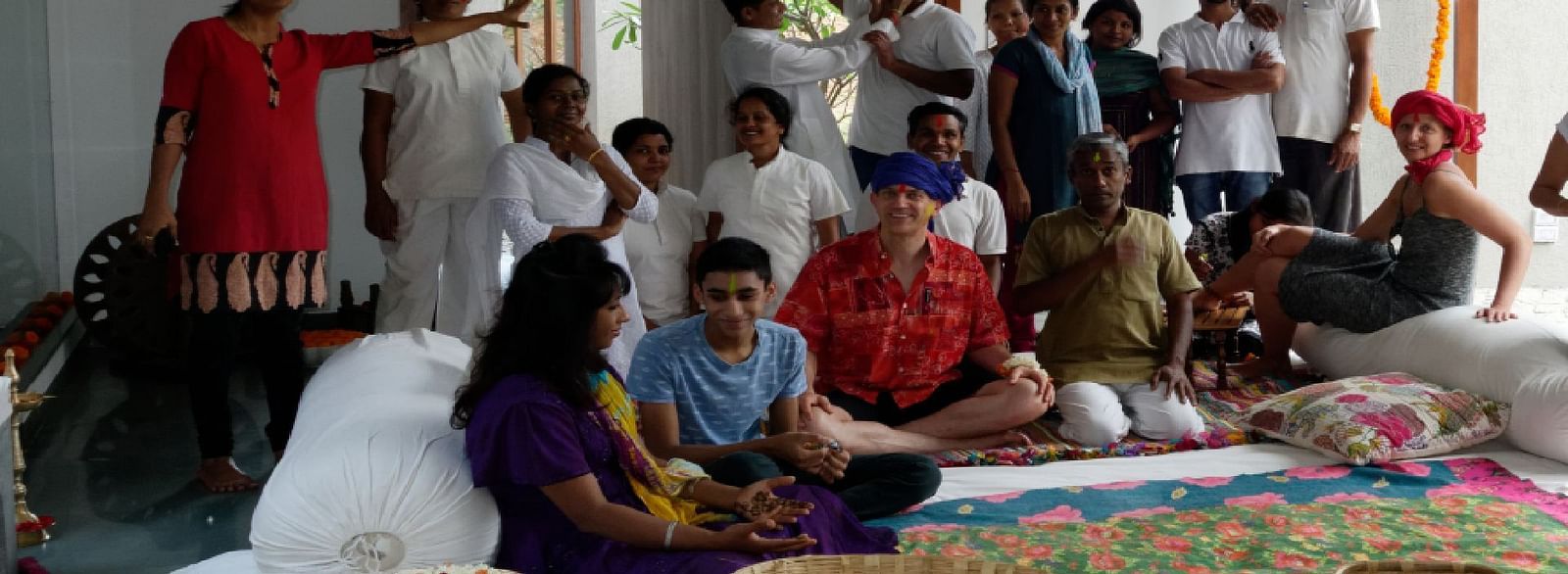 A group of people gathered indoors, some seated on the floor, some standing - Shreyas Retreat
