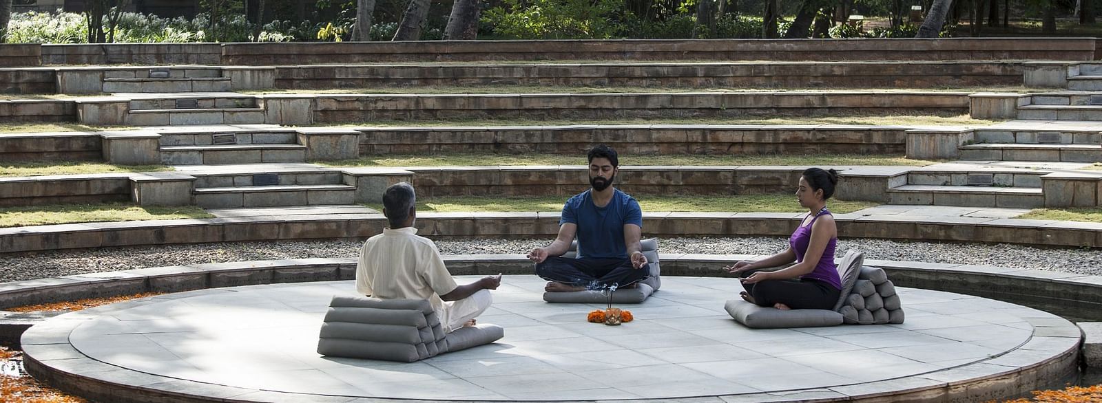 People sitting on a circular platform, outdoor setting, stone steps - Shreyas Retreat