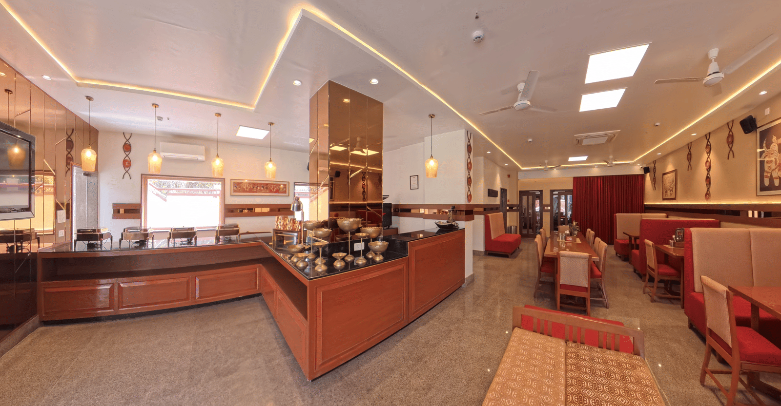 A wide view of a restaurant featuring a wooden buffet service counter and dining tables with chairs | AgraOne – A Boutique Hotel by Dayal Lodge