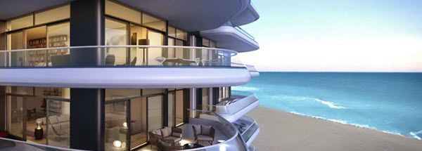 The exterior view of a multi-storey curved building with balconies facing the sea and the beach below.