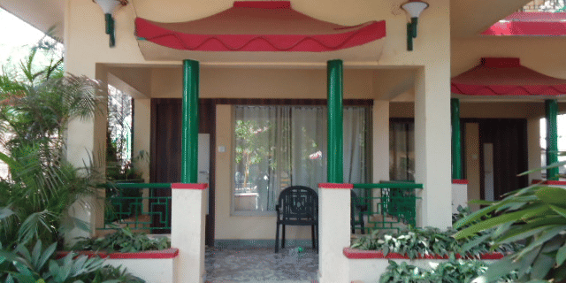 The entrance of the Regent Deluxe room with its front patio and beige, red, and green decor.